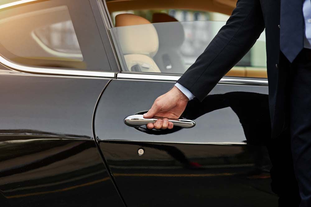 Chauffeur ready to open car door for passenger